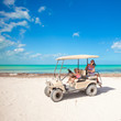 © travnikovstudio - two daughters and their mother driving golf cart at tropical