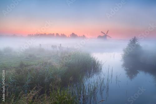 Fototapeta na wymiar windmill and river with dense fog