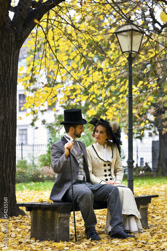 Photographie Old-fashioned dressed couple on a park bench in fall.