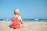 Fototapeta Pomosty - Little girl sitting on sand at beach