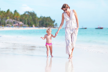 Mother and little daughter walking on the beach