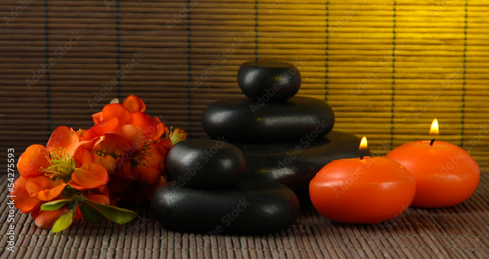 Spa stones with flowers and candles on bamboo background