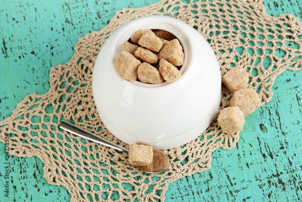 Unrefined sugar in white sugar bowl on wooden background