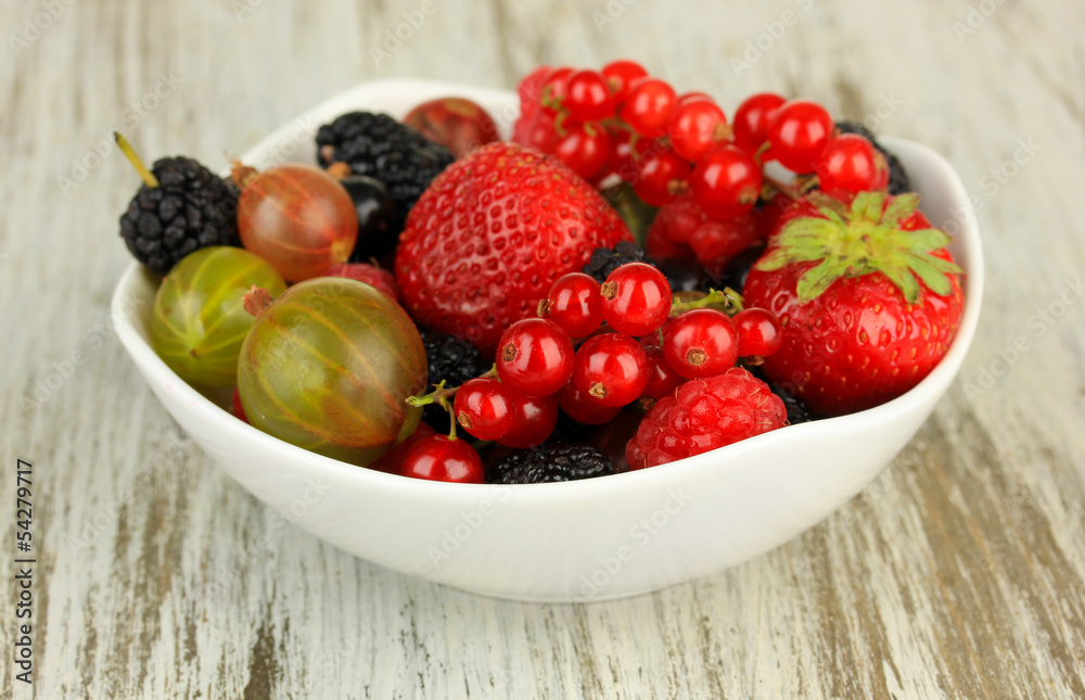 Ripe berries in bowl on table close-up
