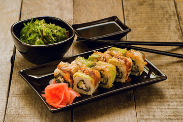 Sushi and chuka seaweed salad with soy sauce on wooden table