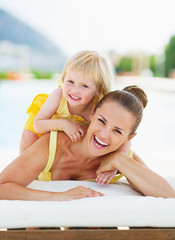 Wall Mural - Portrait of happy mother and baby at poolside