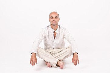 Wall Mural - Man dressed in white sitting relaxing and doing yoga.