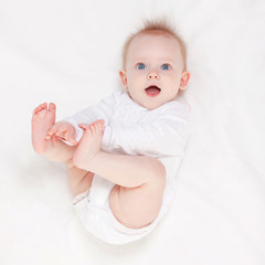 Wall Mural - Cute baby with beautiful blue eyes lying in white bed