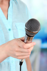 Female with microphone on room background