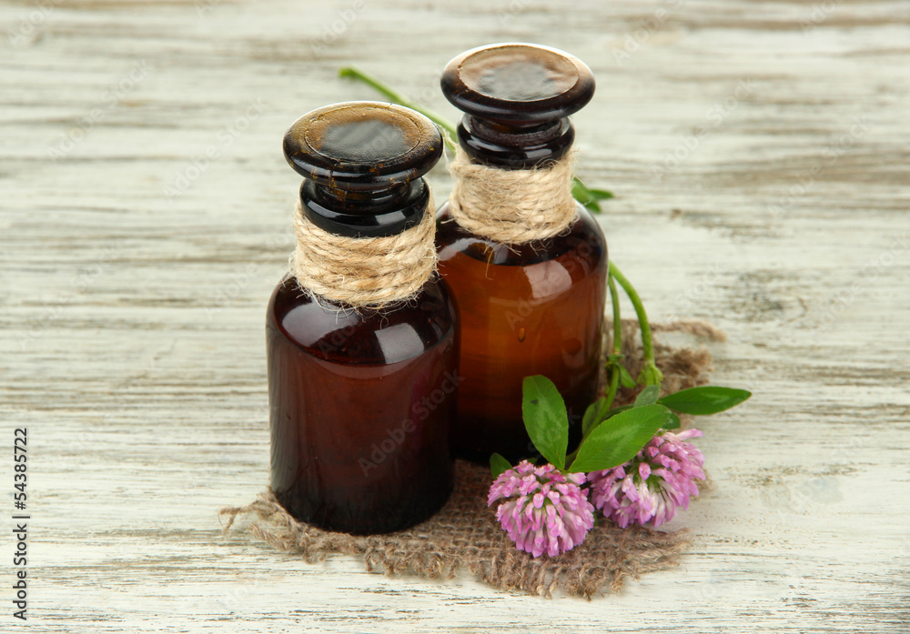 Medicine bottles with clover flowers on wooden table