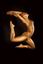 Acrobat Dancer Toned In Gold  Jumping Over Black Background
