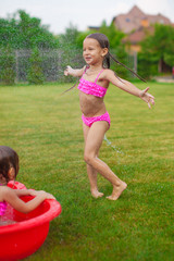 adorable little girl in a swimsuit playing and splashing in the