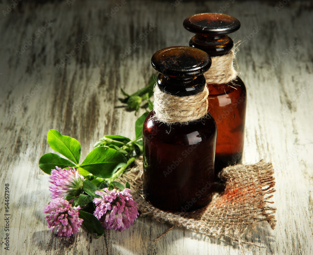 Medicine bottles with clover flowers on wooden table