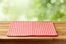 Empty Wooden Table With Checked Tablecloth Over Garden Bokeh