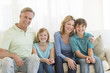© tmc_photos - Family Of Four Smiling Together On Sofa