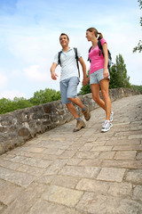 Wall Mural - Couple on a rambling day crossing a roman bridge