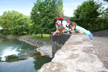 Wall Mural - Man showing fishes from river to kids