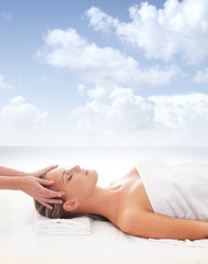 A young woman relaxing on a spa massage on a sky background