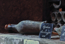 Close-up Of Old Dusty Wine Bottles On A Stone Shelf In A Cellar