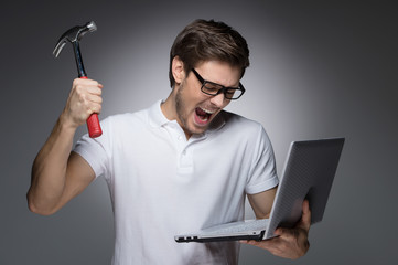 Wall Mural - Bad news. Portrait of furious young men trying to break a laptop