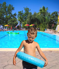 Serious kid stands near the pool in the spa resort