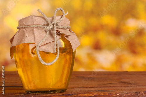 Fototapeta na wymiar Jar of honey on wooden table on yellow background