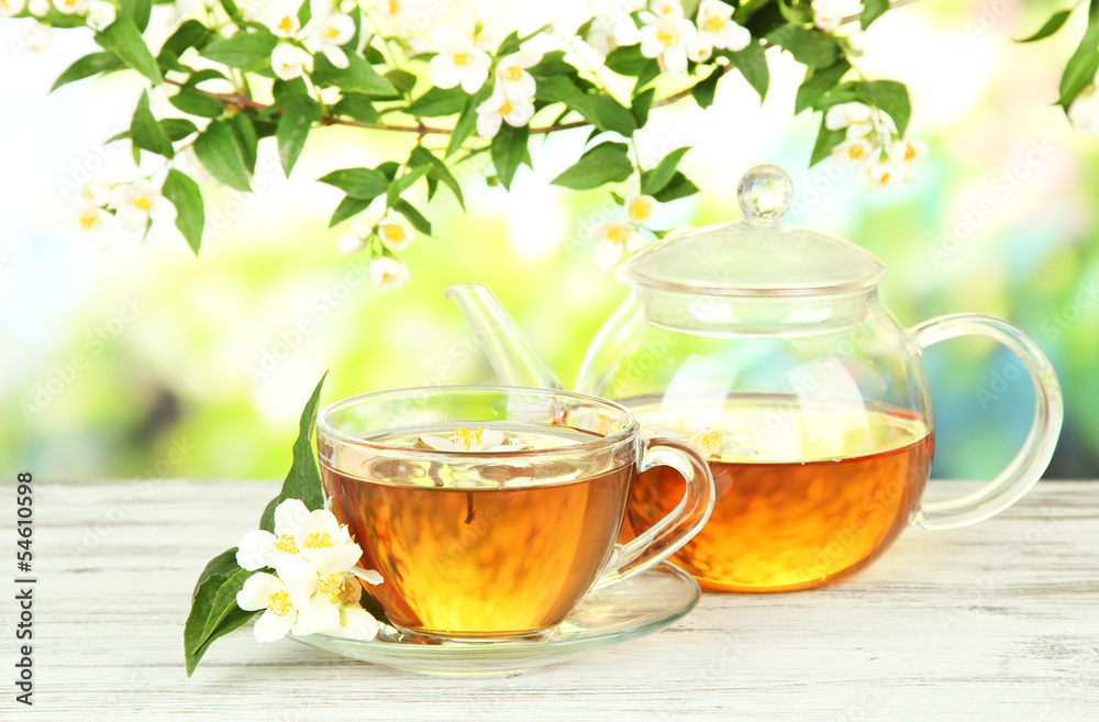 Cup of tea with jasmine, on wooden table, on bright background