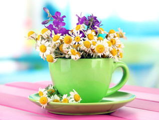 Canvas Print - Bouquet of chamomile flowers in cup, on bright background