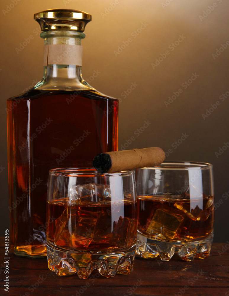 Brandy with ice on wooden table on brown background
