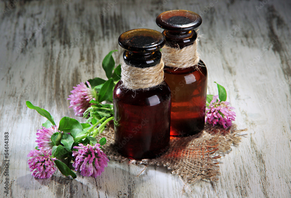 Medicine bottles with clover flowers on wooden table