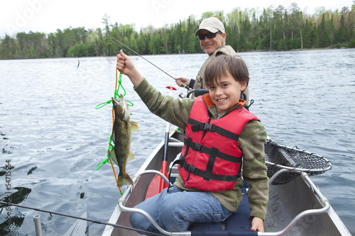 Fotografie, Obraz Young fisherman proudly shows first walleye of the day