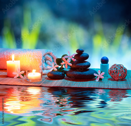 Nowoczesny obraz na płótnie two candles and towels black stones and tiare on water