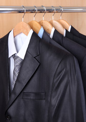 suits with shirts on hangers on wooden background