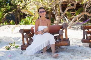 Sticker - Young sexy woman sitting on wooden chair in exotic tropical