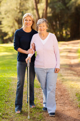 Sticker - senior woman and caring daughter walking in forest