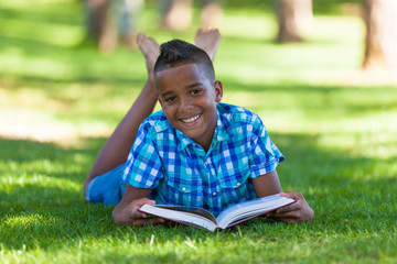 Outdoor portrait of student black boy reading a book - African p