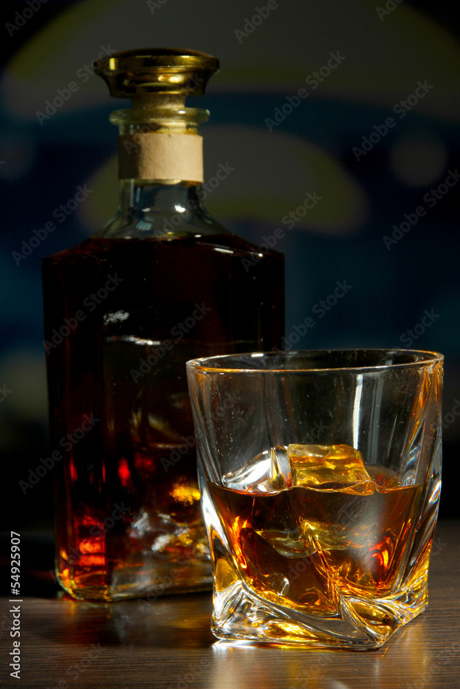 Glass of whiskey with bottle, on dark background