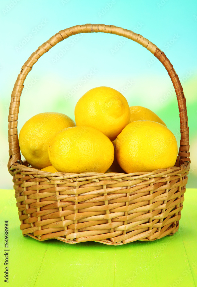 Ripe lemons in wicker basket on table on bright background