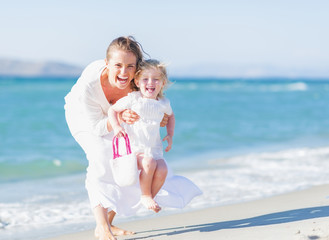 Wall Mural - Happy mother and baby on sea shore having fun