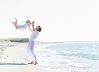 Wall Mural - Happy mother playing with baby on beach