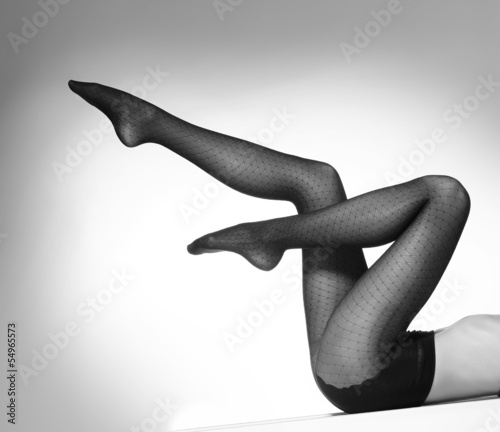 Obraz w ramie Sexy female legs in black erotic stockings on a grey background