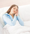 © Acronym - A young brunette Caucasian woman sleeping in a white bed