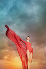 Beautiful woman with red chiffon in front of cloud background