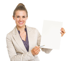 Happy business woman pointing with pen on blank paper sheet