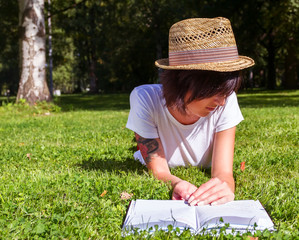 Poster - Beautiful girl hipster lies on meadow and reads the book