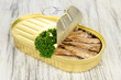 Open tin can with sardines, on wooden background