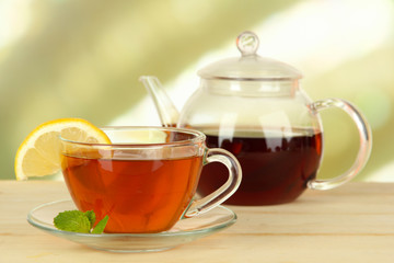 Cup of tea with lemon on table on light background