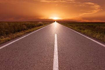 Canvas Print - Driving on empty road towards the setting sun