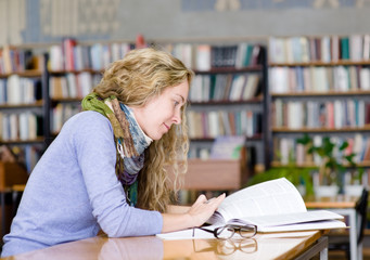 Wall Mural - female student reads the book in library