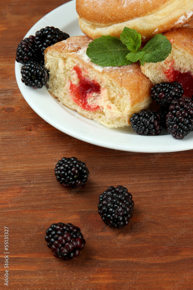 Tasty donuts with berries on wooden table